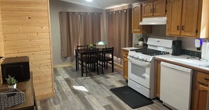 A compact kitchen with wooden cabinets, a stove, and a dishwasher. - Cast a line. Cruise the lake. Explore miles of nearby trails—or simply relax. (Warsaw)