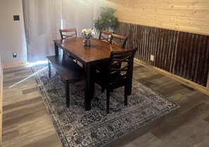 A dining area with a wooden table and chairs, a patterned rug, and a plant. - Cast a line. Cruise the lake. Explore miles of nearby trails—or simply relax. (Warsaw)