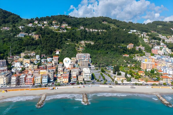 Un pueblo costero con edificios, una playa y un promontorio rocoso en el agua.