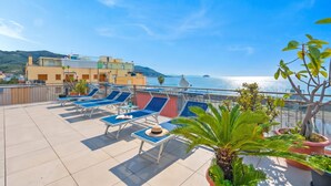 A rooftop terrace with sun loungers, potted plants, and a view of the sea and buildings. - Hotel Del Golfo 59, Laigueglia, Italy (Laigueglia)