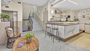 A modern kitchen with a marble island, bar stools, and a staircase leading to an upper floor. - Hotel Del Golfo 59, Laigueglia, Italy (Laigueglia)