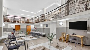 A spacious dining area with high ceilings, a balcony with decorative railing, and a flat-screen TV mounted on the wall. - Hotel Del Golfo 59, Laigueglia, Italy (Laigueglia)