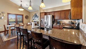 A kitchen with granite countertops, stainless steel appliances, wooden cabinets, and pendant lighting. - Riverfront Condo Steps to Downtown & Lake Michigan (Sheboygan)