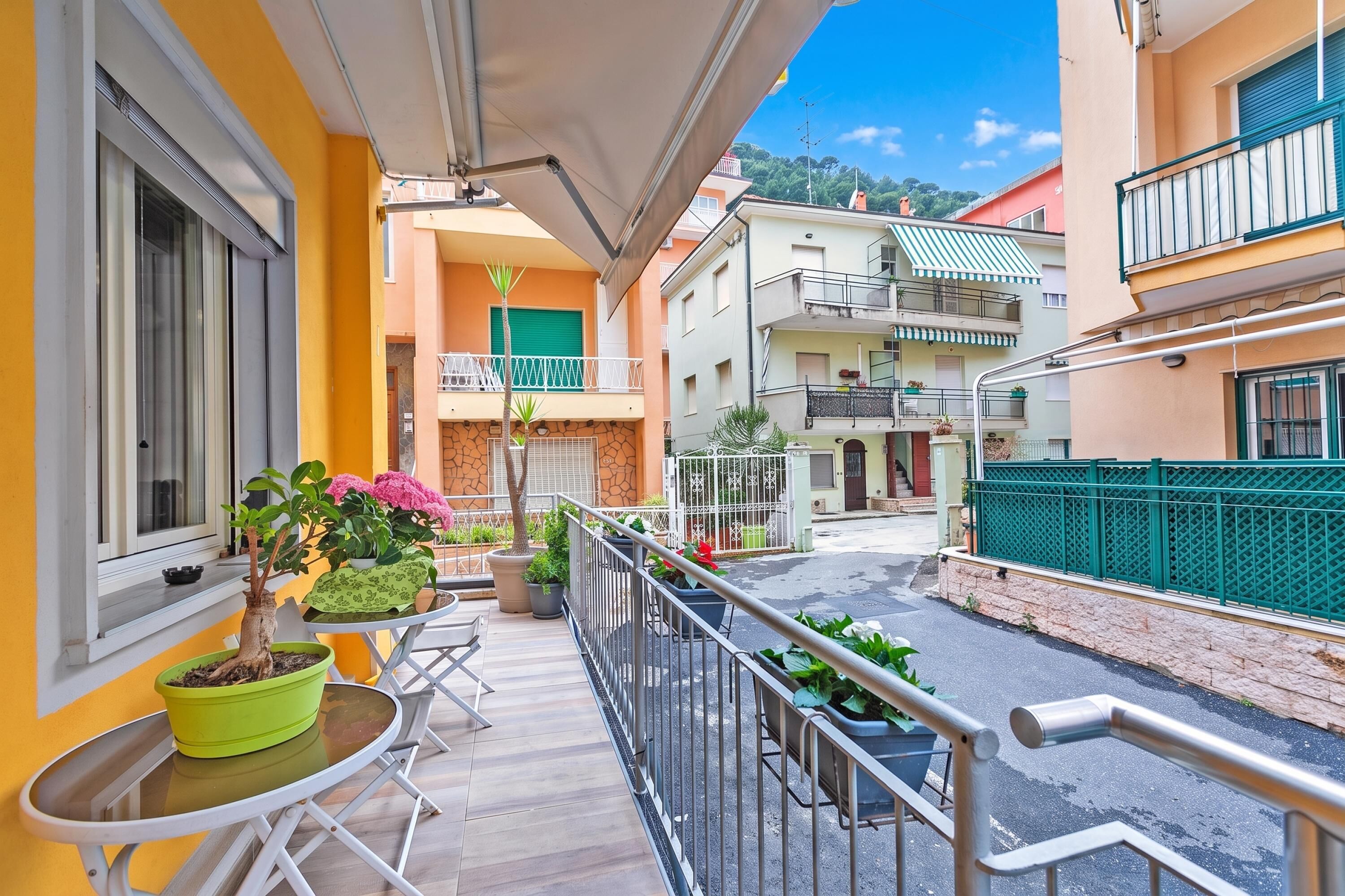 A balcony with potted plants, a table, and chairs.