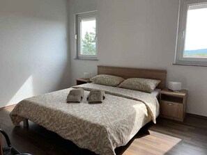 Ein Schlafzimmer mit einem Bett, zwei Nachttischen und zwei Fenstern.