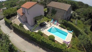 En bostadsfastighet med en swimmingpool, två hus och en asfalterad uppfart.