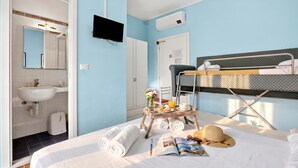 A bedroom with a bunk bed, a bedside table with a newspaper, a hat, and towels. - Hotel Del Golfo 49, Laigueglia, Italy (Laigueglia)