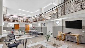 A spacious dining area with high ceilings, a balcony with decorative railing, and a flat-screen TV mounted on the wall. - Hotel Del Golfo 49, Laigueglia, Italy (Laigueglia)