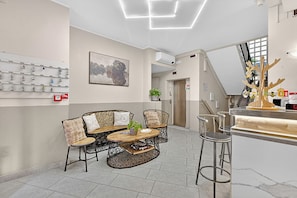 A modern interior with a bar area, seating with patterned chairs, a coffee table, and a wall-mounted display. - Hotel Del Golfo 68, Laigueglia, Italy (Laigueglia)