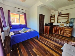 Una habitación con cama, escritorio, dispensador de agua y espejo.