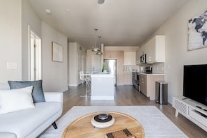 A modern living room with a sofa, a coffee table, and a television. - Top-Floor Luxury Retreat, King Bed, Full Kitchen, Private Balcony (Frisco)
