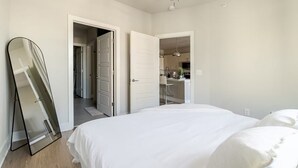 A bedroom with a bed, a door leading to a bathroom, and a hallway.