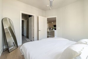 A bedroom with a bed, a door leading to a bathroom, and a hallway.
