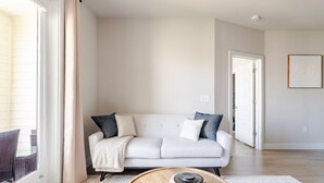 A modern living room with a white sofa, a round coffee table, and a view of the outside.