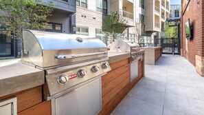 An outdoor kitchen with a grill and a wooden cabinet. - Top-Floor Luxury Retreat, King Bed, Full Kitchen, Private Balcony (Frisco)