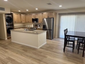 A modern kitchen with a central island, stainless steel appliances, wooden cabinets, and a dining area with a table and chairs. - Casa on 18th-Spacious 3 Bed/2Bath - Central Tucson (Tucson)