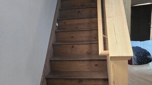 A wooden staircase with a handrail leading to a bedroom. - Historical, non Smoking, loft cottage with beautiful garden  near Riverwalk (Pueblo)