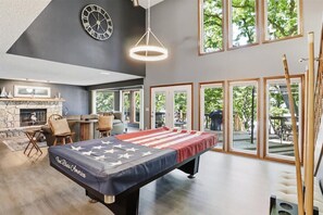 Een pooltafel met een tafelkleed met Amerikaanse vlag, een klok en een stenen openhaard.