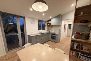 Una cocina moderna con comedor, ventanas amplias y una estantería.