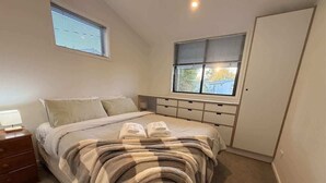 Une chambre à coucher avec un lit, une table de chevet, une fenêtre et une armoire.