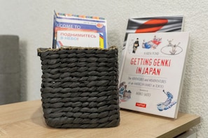 Ein geflochtener Korb auf einer Holzoberfläche, neben ihm zwei Bücher.