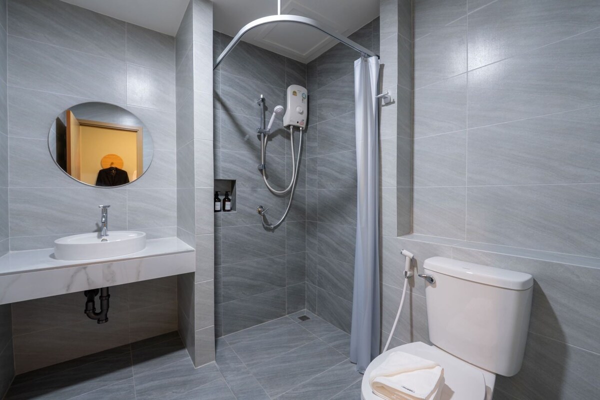 A modern bathroom with a shower, toilet, sink, and a mirror.