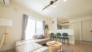 A modern living room with a sofa, a coffee table, and a dining area with chairs. - Furano Ezo Murasaki B (Furano)