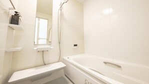 A bathroom with a bathtub, a sink, a mirror, and a shower. - Furano Ezo Murasaki B (Furano)