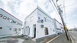 A modern building with a white facade, multiple windows, and an air conditioning unit. - Furano Ezo Murasaki B (Furano)