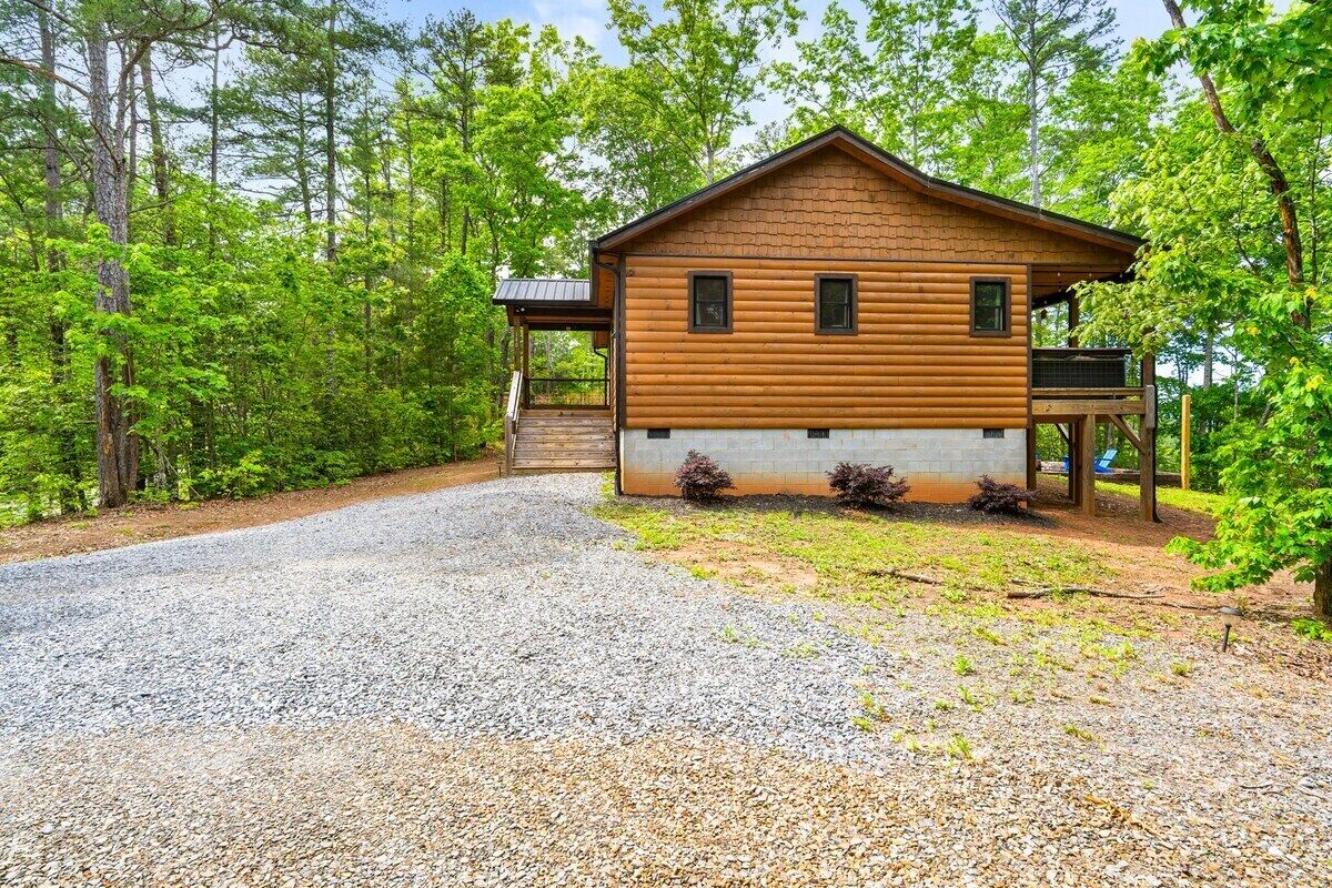 A wooden cabin with a porch, surrounded by trees.