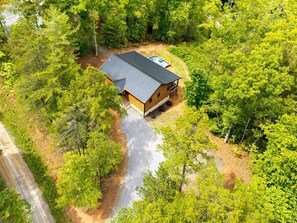 A cabin with a sloped roof, surrounded by dense forest. - Cozy Cabin with Great Views • Hot Tub • Wi-Fi (Murphy)