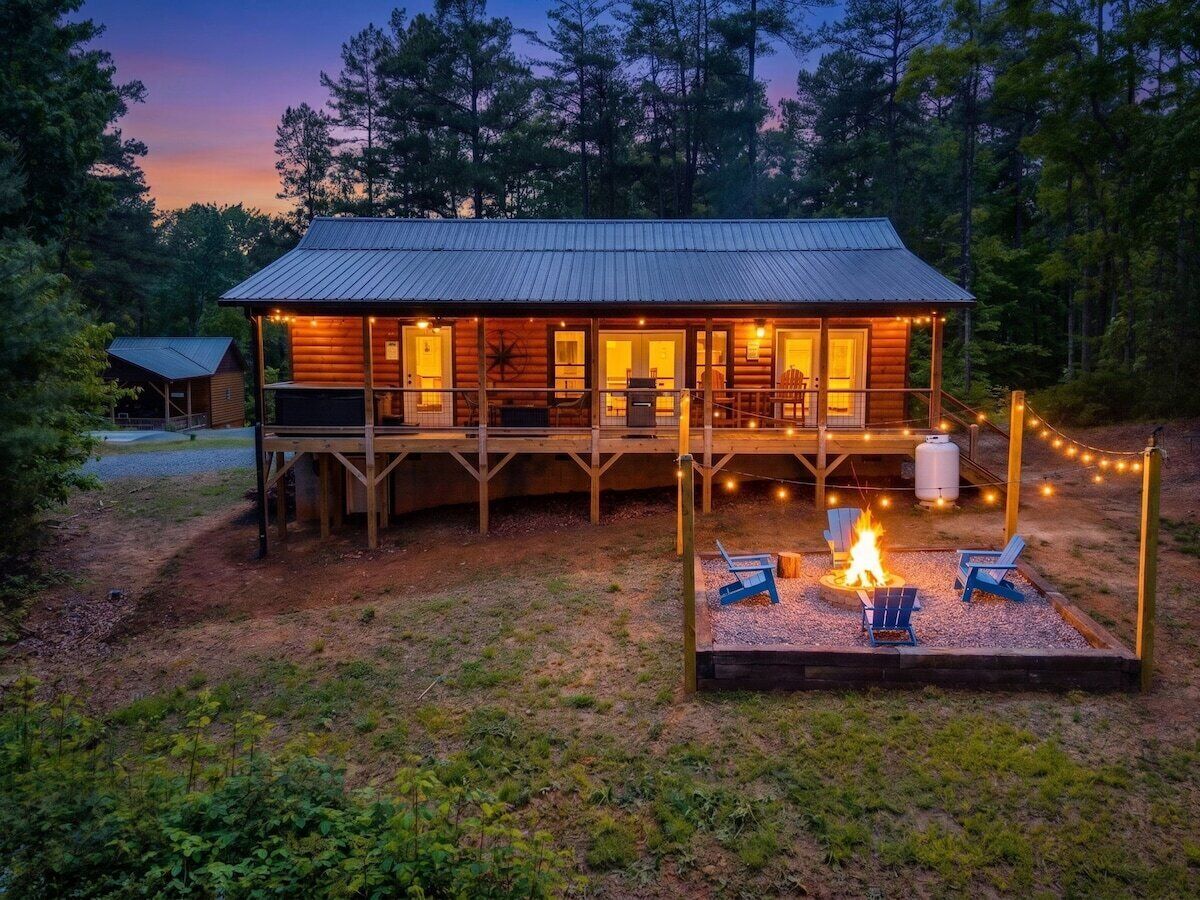 A cabin with a deck, a fire pit, and string lights.