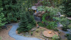 Ein Haus, umgeben von dichtem Wald, mit einem Kiesweg, der zum Eingang führt.