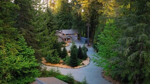 Ein Haus, umgeben von dichtem Wald, mit einer Auffahrt zum Eingang.