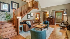 A spacious living room with a wooden staircase, a sofa, a coffee table, and a chair.
