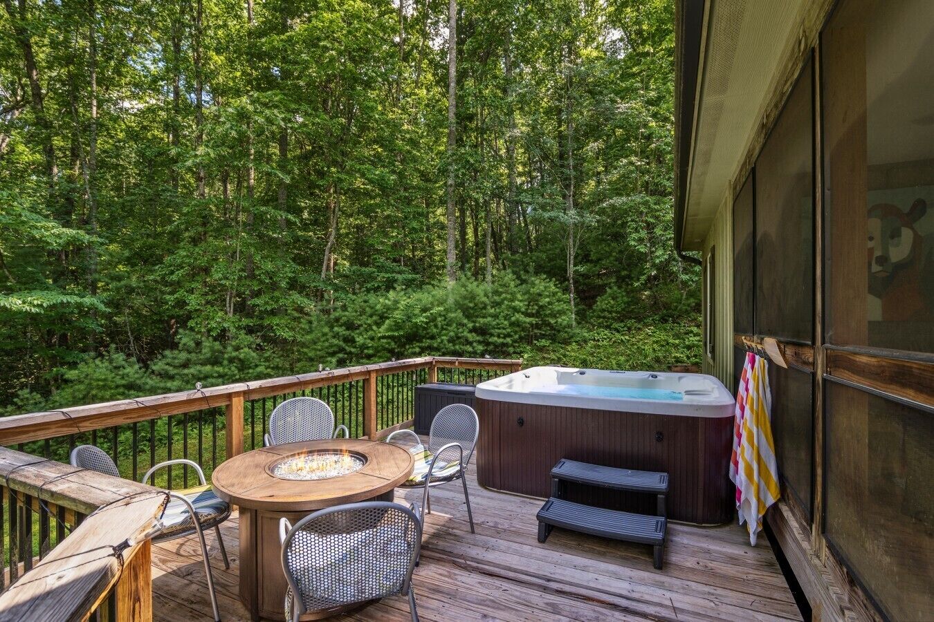 Eine Terrasse mit Whirlpool, Sitzgelegenheiten und einem Feuerkorb.