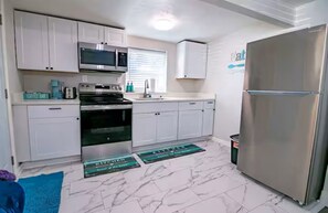 A kitchen with white cabinets, stainless steel appliances, and a marble floor. - Sapphire Stay. Walk to AT&T Stadium! Pet Friendly! (Arlington)