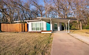 A modern single-story house with a covered porch, a fenced backyard, and a clear sky. - Sapphire Stay. Walk to AT&T Stadium! Pet Friendly! (Arlington)