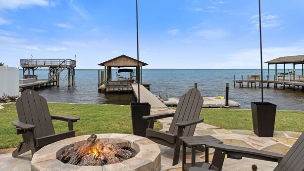 A lakeside patio with Adirondack chairs, a fire pit, and a gazebo. - Private Dock Waterfront Home in Miramar (Miramar Beach)