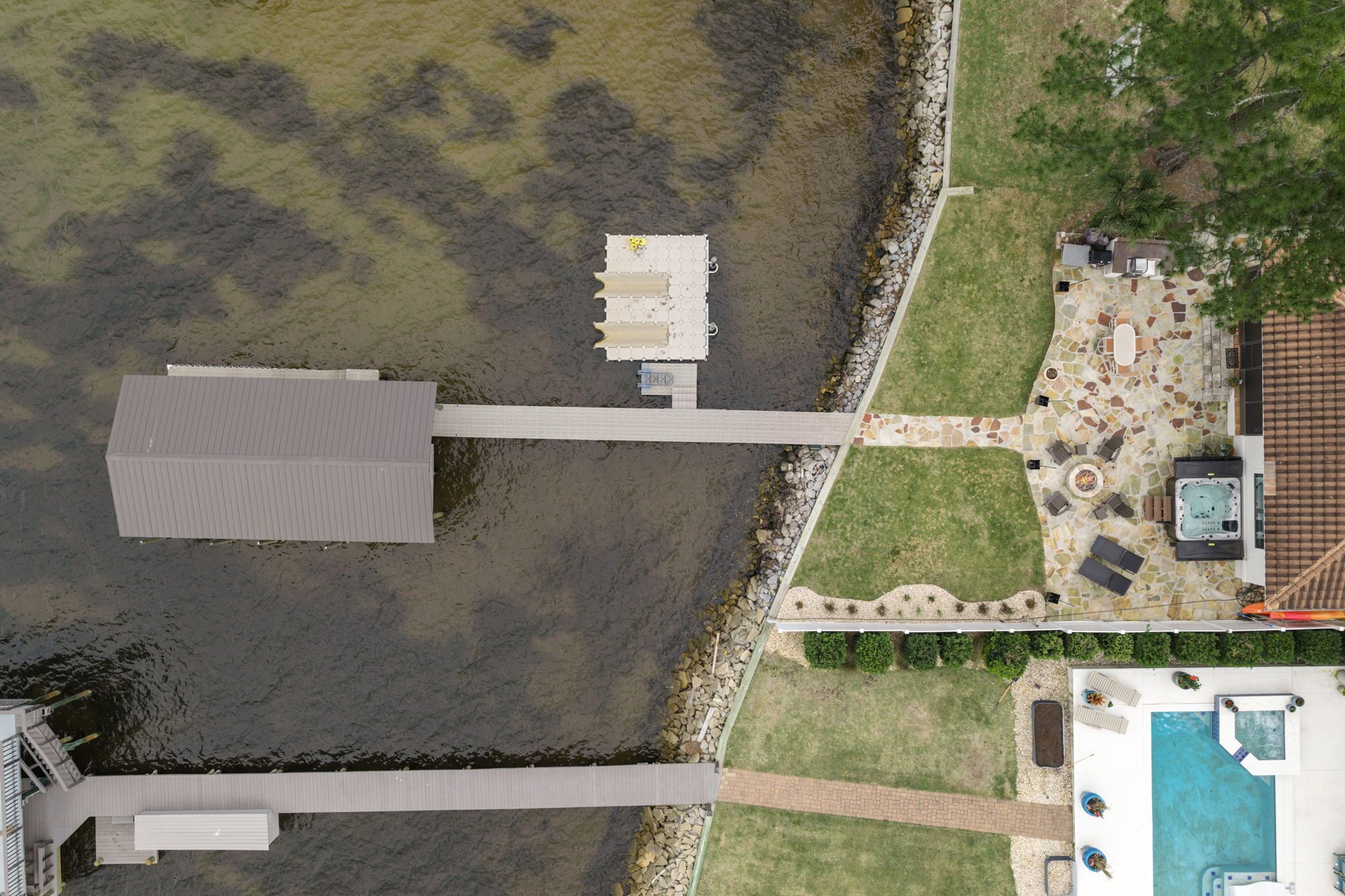 Vista aérea de una propiedad con muelle, piscina y zona de patio.