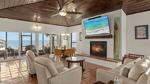 A spacious living area with a fireplace, comfortable seating, a television, and large windows offering a view of the ocean. - Private Dock Waterfront Home in Miramar (Miramar Beach)