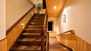 Una escalera de madera con barandilla, paredes de madera y un techo con vigas de madera.