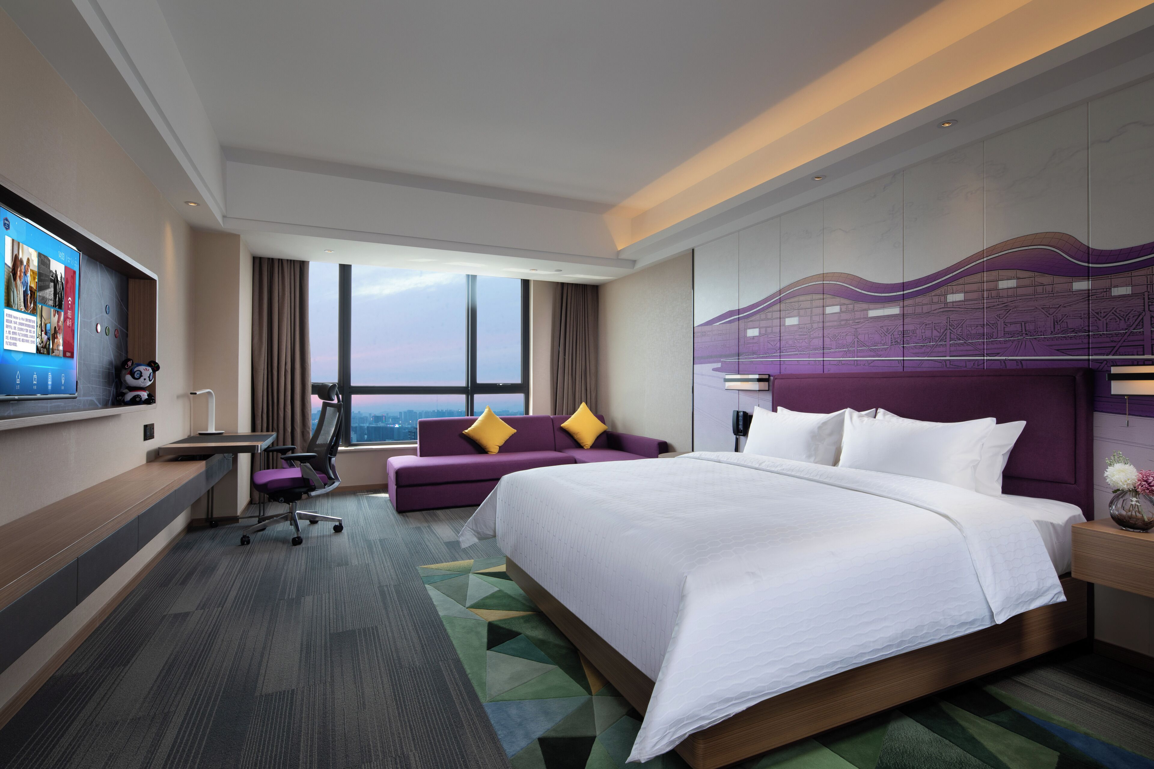 A modern hotel room with a large bed, a sofa, a desk, and a TV.