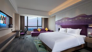 Une chambre d’hôtel moderne, dotée d’un grand lit, d’un canapé, d’un bureau et d’une télévision.
