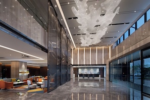 Eine moderne Lobby mit Empfangstresen, Sitzgelegenheiten und großen Fenstern.