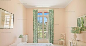 A bedroom with a bed, a chair, a desk, a window with curtains, and a mirror. - Nouveau Le Rooftop - Clim chambres Et Piscine (HYERES)