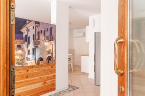 A modern kitchen with white cabinets, a stainless steel refrigerator, and a wooden door with a glass panel. - *Alle porte* [modern apartment] (Vittorio Veneto)
