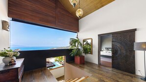 Ein modernes Zimmer mit großem Fenster und Meerblick, das eine Holzbalkendecke aufweist.