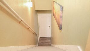 Eine Treppe mit Handlauf, eine weiße Tür oben und ein an der Wand hängendes Bild.