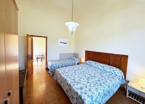 Ein Schlafzimmer mit zwei Betten, einem Holzkopfstück, einer Hängelampe und einer Tür zu einem anderen Raum.